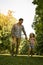 Father running in the meadow with daughter.