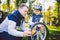 Father`s day Caucasian dad and 5 year old son in the backyard near the house on the green grass on the lawn repairing a bicycle,