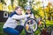 Father`s day Caucasian dad and 5 year old son in the backyard near the house on the green grass on the lawn repairing a bicycle,