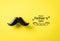 Father`s day concept. Black moustache on yellow paper background