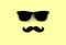 Father`s day concept. Hipster black sunglasses and funny moustache on yellow background