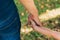 Father`s day. Dad and son. Dad holds the hand of a little son in the park. Little child holding hands with his father outdoors.