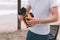 Father`s day. Young dad in a white T-shirt and seated shorts holds in his hands an orange toy car on the beach.