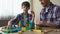 Father and serious son playing with toy cubes, building house together, leisure