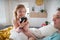 Father setting alarm clock with his little daughter with Down syndrome in bed at home.