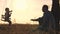 Father shakes his little daughter on a swing in the glare of the sun, dad and kid play samlet at sunset, soar in the air