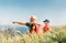 Father showing something interesting to his teenager son sitting on the grass during their mounting hiking walking