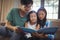 Father and siblings watching photo album together in living room