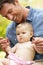 Father Sitting With Baby Girl In Field