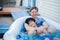 Father sitting in hot tub with disabled son outdoors laughing