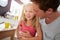 Father Sitting With Laughing Daughter At Breakfast Table