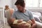 Father Sitting In Nursery Chair Holds Sleeping Baby Son