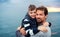 Father with small son on a walk outdoors standing on beach at dusk.