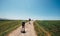 Father and son backpacker travelers walk on countryside road across field