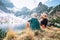 Father and son backpackers sit near the mountain lake and enjoy