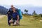 Father and son with backpacks hiking together in scenic summer green mountains. Dad and child standing enjoying landscape mountain