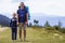 Father and son with backpacks hiking together in scenic summer green mountains. Dad and child standing enjoying landscape mountain