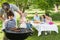 Father and son at barbecue grill with family having lunch in park