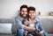 Father and son bonding. Happy dad embracing boy, posing and smiling to camera, sitting on couch at home