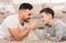 Father and son compete in arm-wrestling, lying on floor at home