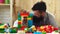 Father and son create colorful constructions with toy bricks. Happy child playing with dad baby sitter building