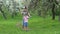 Father with son and daughter on shoulders have fun in garden. Slow motion