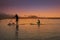 father and son enjoying the sunset sailing on paddle board