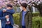 Father and son with a face mask are in the city outdoor, blooming trees, spring season, flowering time - concept of allergies and