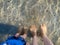 Father and son feet on shallow beach water