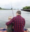 Father and son fishing. Dad shows his son how to hold the spinning and spin the reel. Fishing training on a pond or river. Caring