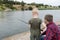 Father and son fishing. Dad shows his son how to hold the spinning and spin the reel. Fishing training on a pond or river. Caring