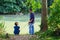 Father with son fishing at river bank, summer outdoor. Man and young boy standing at river bank with rod and fishing. Family