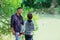 Father with son fishing at river bank, summer outdoor. Man and young boy standing at river bank with rod and fishing. Family