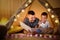 Father and son with flashlight reading book in tent