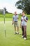 Father and son golfing. Full length of father and son standing on the putting green with golf clubs and smiling.