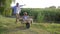 Father and son have fun with hands up, parent tickles little boy sitting in a wheelbarrow at village