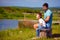 Father and son having fun, sitting on the bench by the lake on sunny summer day