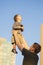 Father and Son Having Fun Together Outdoors.Dad Tossing Son Up Against Blue sky