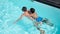 Father with son on his back swimming in pool