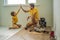 Father and son installing new wooden laminate flooring on a warm film floor. Infrared floor heating system under