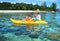Father and son kayaking next to tropical coral island