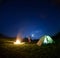 Father and son near campfire and tent under night sky