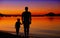 Father and son near the water edge at sunset