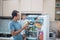 father and son open refrigerator at home looking for some food