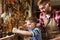 Father and son with plane shaving wood at workshop