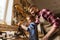 Father and son with plane shaving wood at workshop