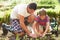 Father And Son Planting Seedling In Ground On Allotment