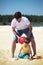 Father with son play with ball on sand