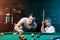 Father and son play billiards. The father teaches his son to play billiards. The concept of parents and children, upbringing,