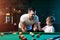 Father and son play billiards. The father teaches his son to play billiards. The concept of parents and children, upbringing,